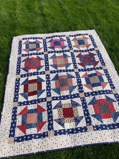 a quilt is laying on the grass with it's center piece in red, white and blue