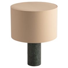 a lamp that is sitting on top of a wooden table with a beige shade over it