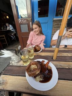 two people sitting at a table with plates of food and drinks in front of them