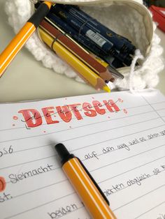 a notepad with the word deutsch written on it next to pencils and crayons