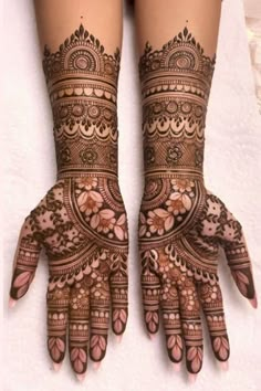 two hands with henna tattoos on them, one is showing off the intricate design