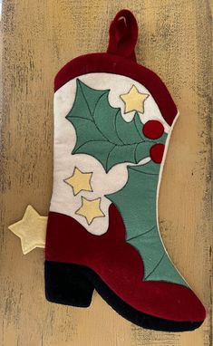 a christmas stocking hanging on the side of a wooden door with holly and stars