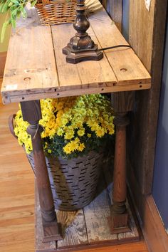 a wooden table with yellow flowers in a basket on the floor next to a door