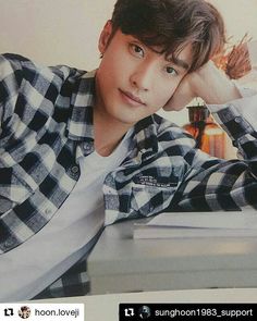 a young man sitting at a desk with his hand on his head and looking off to the side