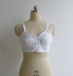 "Brand new vintage deadstock from the 1970's. Soviet era white longline bra top in 100% cotton. Features darted bra cups with circle stitching to the bottom half, slim shoulder straps & a sweet picot trim to the bustline. Closes with a column of buttons to the center front. Could be worn as an undergarment, or even as a cropped camisole top. 100% cotton takes dye well & could be a fun project too! Check out other brassieres in the shop - www.etsy.com/shop/fivestonesvintage?section_id=100 Fitted Cotton Crop Top With Built-in Bra, Retro Fitted Cotton Tank Top, Fitted Retro Cotton Tank Top, Fitted Cotton Camisole For Daywear, Cotton Underbust Tops For Summer, White Tops With Built-in Bra And Underbust Shape, Summer Vintage Top With Built-in Bra, Fitted Cotton Tops With Removable Bra Pads, Vintage Fitted Spaghetti Strap Tops