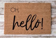 a welcome mat with the word hello written on it in black ink against a white wood background