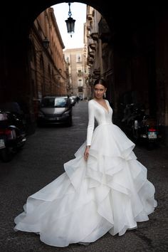 a woman in a wedding dress standing on the street