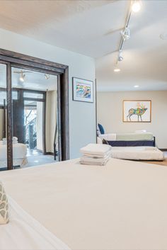 a bedroom with white bedding and large glass doors leading to the outside patio area