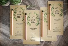 three wedding stationery cards with pencils and greenery on them, sitting next to each other