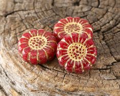 two red flowers sitting on top of a piece of wood next to a tree stump