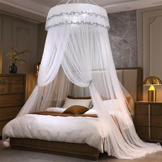 a white canopy bed in a bedroom next to a night stand