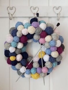 a yarn wreath hanging on the wall with knitting needles