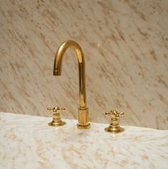 two golden faucets on a marble counter top