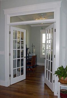 an open door leading into a living room with hardwood floors and white trim on the walls