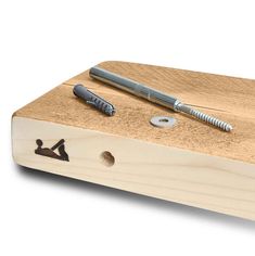 a pen and screwdriver sitting on top of a piece of wood with holes in it