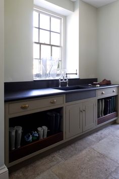 a kitchen with a sink, cabinets and window in the corner on the far wall