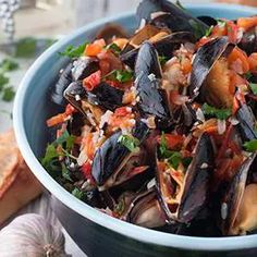 a blue bowl filled with mussels and vegetables