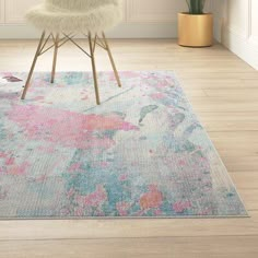 a white chair sitting on top of a wooden floor next to a rug covered in pink and blue flowers