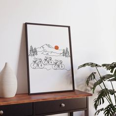 a black and white photo sitting on top of a wooden table next to a potted plant