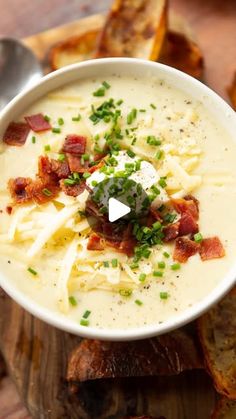 a bowl of potato soup with bacon and sour cream in it on a cutting board