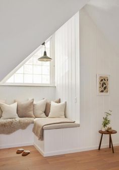 a room with white walls and wooden flooring has a window seat on the far wall