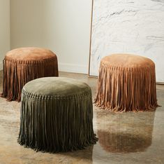 two stools with fringed skirts on them in front of a wall and floor