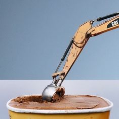 an excavator scooping chocolate into a yellow bucket with blue sky in the background