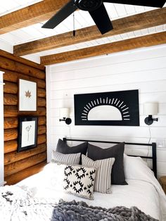 a bedroom with wood paneled walls and white bedding, black and white throw pillows