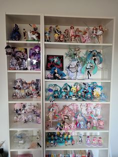 a book shelf filled with lots of anime figurines on top of white shelves