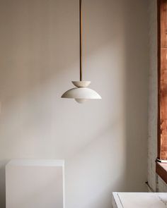 a light fixture hanging from the ceiling in a room with white walls and flooring