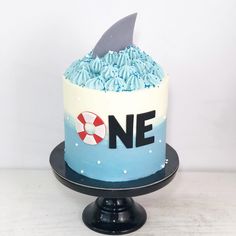 there is a cake with blue frosting and a shark fin on the top that says one