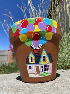 a potted plant with a house and balloons painted on it