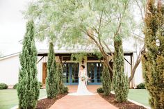 a bride standing in front of a white building surrounded by trees