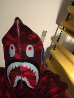 a person wearing a red camo hoodie with a shark face painted on it