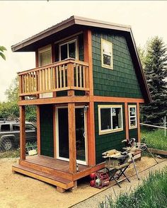 a small green house with a porch and balcony