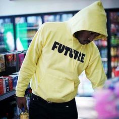 a man wearing a yellow hoodie with the word future written on it in black