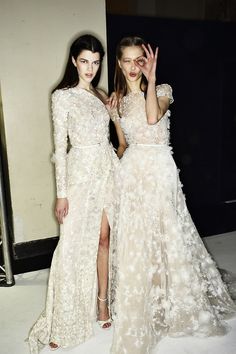 two women in white dresses standing next to each other