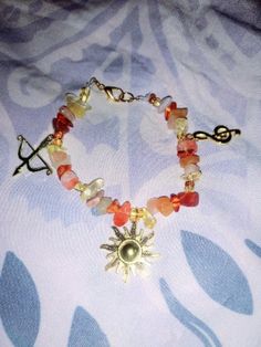 a bracelet with beads and charms on top of a white cloth covered tablecloth in front of a blue flowered background