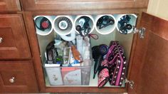 there are many items in the cabinet and it is organized with scissors, hairbrushes, toothpaste, and other personal care products