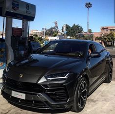 a black sports car parked in front of a gas pump