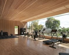 there are many treadmills in the room with wood walls and flooring that is very large