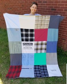 a man is holding up a quilt made out of different colored plaids on the grass