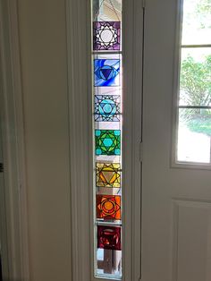 a colorful stained glass window on the side of a white door in front of a doorway