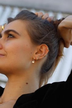 a woman with her hair in a bun and wearing gold ear climbrs on top of her head