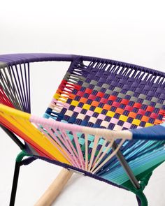 a multicolored chair sitting on top of a white floor next to a wooden stick