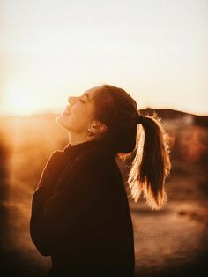 a woman with long hair standing in the sun