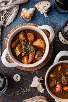 two bowls filled with stew and bread on top of a table