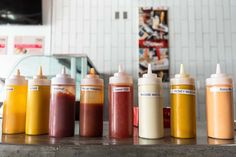 six different sauce bottles lined up on a counter