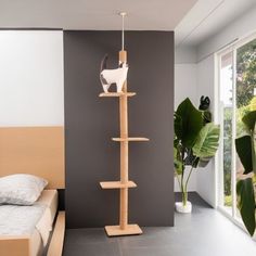 a cat sitting on top of a wooden shelf next to a bed in a room