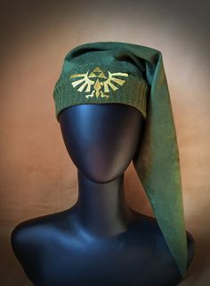 a hat on top of a mannequin head wearing a green cap with the legend of zelda emblem